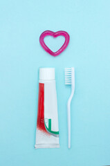 Closeup of a toothpaste, toothbrush and toothpaste heart on blurred blue background. Means to care for the oral cavity.