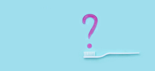 New white toothbrush with toothpaste question on blurred blue back. Close-up on a blue background. Professional Dental concept. Means to care for the oral cavity. Concept of oral hygiene in family.