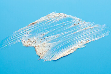 A sample of a cosmetic skin scrub with apricot pits. Blue background.