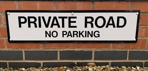 Private Road No parking sign attached to a red and blue brick wall up close UK