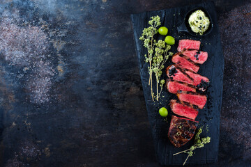 Barbecue dry aged angus roast beef steak with herb butter and dried oregano served as top view on a...