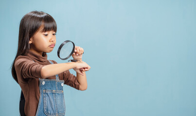 A little girl is using a magnifying glass to look at insects.