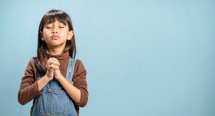A little girls is putting their hands together to pray for God's blessings.