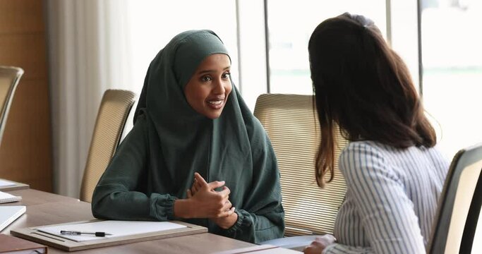 Somalian businesswoman in hijab shake hands colleague after meeting in office boardroom, achieving agreement, sell or buy company services, finish negotiations feel satisfied with deal and cooperation