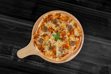 Freshly baked pizza with cheese and tomatoes served on a wooden table and board