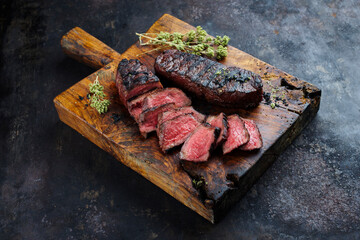Barbecue dry aged angus roast beef steak with herb butter and dried oregano served as close-up on a rustic cutting board with copy space