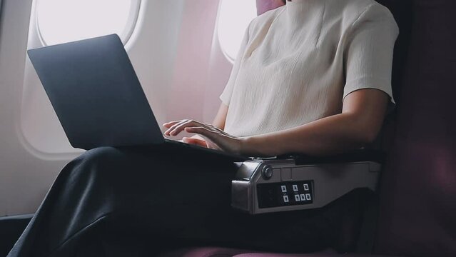 Woman using laptop while is sitting in plane near window..