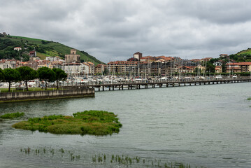 Fototapeta na wymiar Skyline of the Zumaya village with the marina crowded of boats in Urola estuary in the foreground on a stormy day, Gipuzkoa, Basque Country, Spain