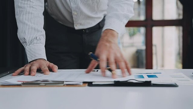 Group of confident business people point to graphs and charts to analyze market data, balance sheet, account, net profit to plan new sales strategies to increase production capacity.