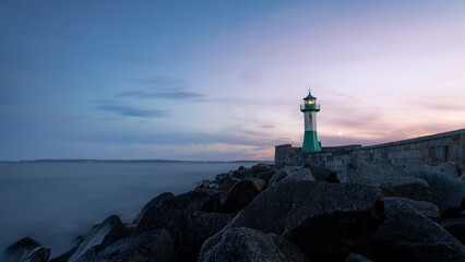 The beautiful lighthouse on the pier of Sassnitz on the island of Rügen after the sunset. The rugged rocks in the foreground make a nice contrast to the soft water.
