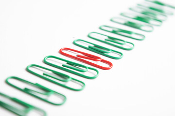 Red paper clip in between green, unique concept