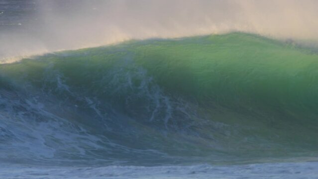 huge wave crashing in the ocean at sunset