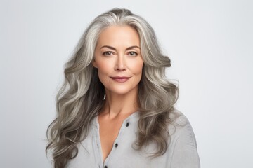 Fototapeta premium A serene and confident mature Caucasian woman in her 50s or 60s, radiating natural beauty and happiness in a studio portrait.