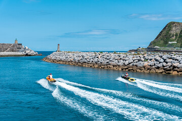 Two jet skis sailing down the Urola river towards the Cantabrian Sea on a sunny day, Zumaia,...