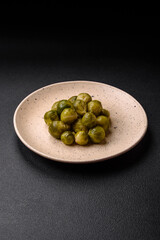 Delicious boiled Brussels sprouts on a ceramic plate on a dark concrete background