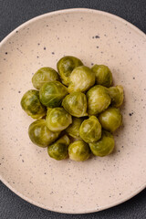 Delicious boiled Brussels sprouts on a ceramic plate on a dark concrete background