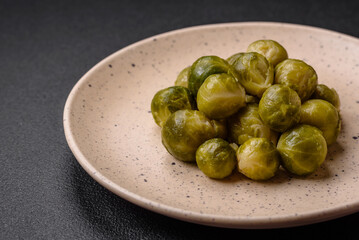 Delicious boiled Brussels sprouts on a ceramic plate on a dark concrete background