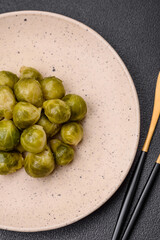 Delicious boiled Brussels sprouts on a ceramic plate on a dark concrete background