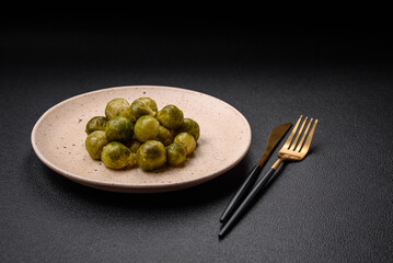 Delicious boiled Brussels sprouts on a ceramic plate on a dark concrete background