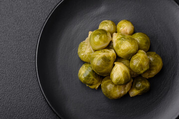Delicious boiled Brussels sprouts on a ceramic plate on a dark concrete background