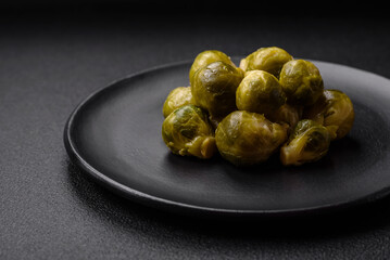 Delicious boiled Brussels sprouts on a ceramic plate on a dark concrete background