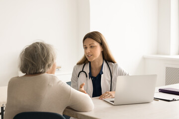 Young female therapist consulting pensioner patient, listen to complaint, explain disease treatment, gives medical advice. Older woman pass health diagnostic in hospital. Healthcare, medical services