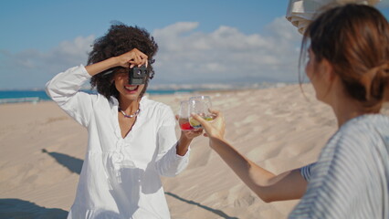 Girls taking beach pictures at ocean coast. Happy african american using camera