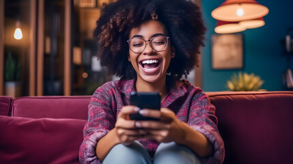 Excited happy young black woman holding smart phone device sitting on sofa at home - obrazy, fototapety, plakaty