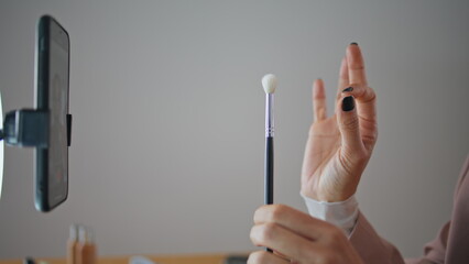 Visagiste fingers cosmetics brushes review at house closeup. Woman reviewing