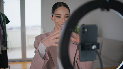Blogger woman adjusting smartphone at tripod at room. Influencer recording video