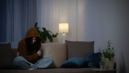 sad teenager girl sitting on couch indoor at night