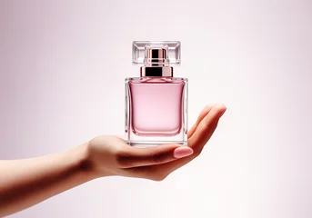 Foto op Plexiglas Female hand holds an elegant light pink perfume bottle. AI generated © Alicina