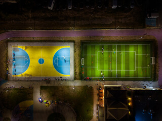 An aerial view of an evening sports ground with soccer and baske