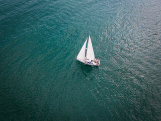 Aerial view of a sailboat gracefully gliding across the boundless waves of the sea.
