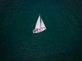 Aerial view of a sailboat gracefully gliding across the boundless waves of the sea.