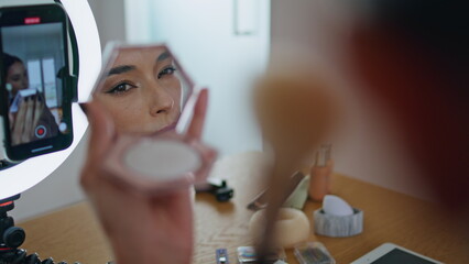 Influencer woman applying makeup looking mirror at house closeup. Blogger visage