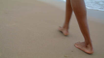 Slim legs walking beach at ocean waves closeup. Woman stroll leaving footprints