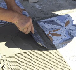 A man, a builder, aligns the mortar under the paving slabs