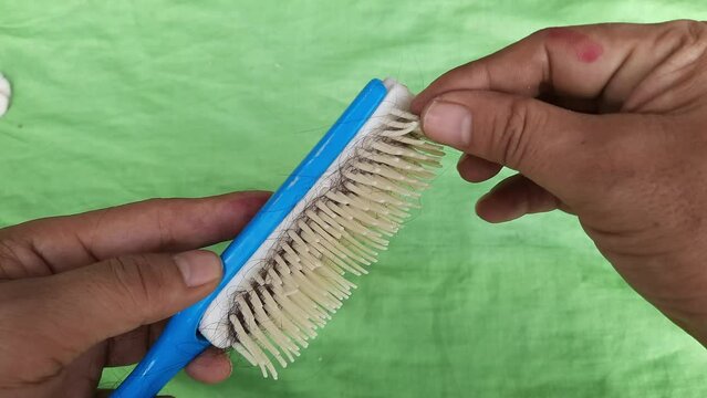 Cleaning a comb from hair residue, a man holding a hair straightener on a green background, 4k footage shot from above