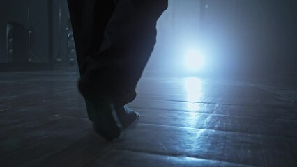 Young woman entering stage with smoke on background. Close-up of woman legs entering stage. Elegant female heels dancer. Silhouette of dancer legs walking through dark studio. Tracking shot in 4K, UHD