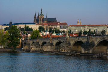 Fototapeta na wymiar Panoramic view from the Vltava River to the historic Prague Castle and bridge of Charles in the morning sun