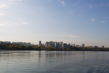 Fototapeta premium city skyline. Building and skyscraper nearby the river. landscape of a big river with steep banks. clouds over the blue river. dawn over the lake
