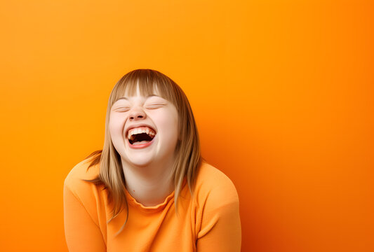 Portrait of a happy girl/woman with down syndrome on an orange background