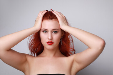 Obraz premium Indoor portrait of stunning young woman with long red hair over white wall.