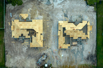 Aerial view of builders working on unfinished residential house with wooden roof frame structure...