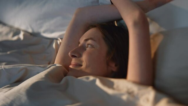 Happy woman stretching bed in sunlight closeup. Carefree smiling girl waking up