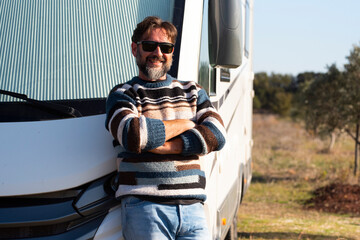 One man posing and smiling at the camera outside a new modern camper van motorhome vehicle. Concept...