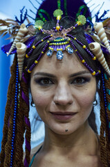 A close-up portrait of a dark-haired girl, she has artificial dreadlocks and jewelry on her head. Photo of an excited dancer before a performance.