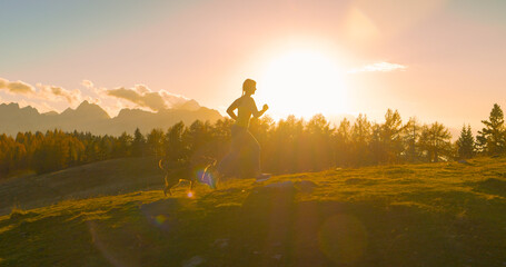 CLOSE UP, LENS FLARE Amazing sunset and lady running on top of hill with her dog