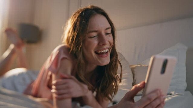 Laughing woman talking online conference closeup. Relaxed morning girl lying bed